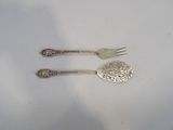 two silver spoons and a fork on a white surface
