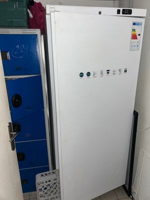 un réfrigérateur blanc dans un coin de la pièce, à côté d'un placard bleu