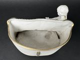 a white bowl with a doll in it on a black table