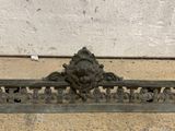 an antique cast iron fireplace grate with a lion head on it