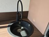 a sink in the corner of a kitchen with a black faucet