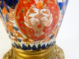 a blue vase with a gold base on a white surface