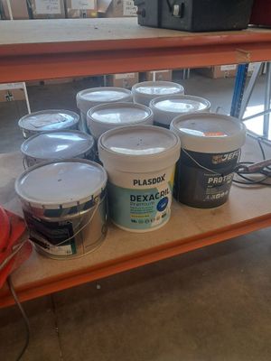 several buckets of paint are sitting on a shelf in a room