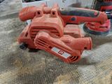 une ponceuse rouge posée par terre à côté d'une boîte à outils