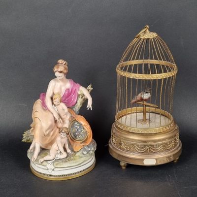 two figurines of a woman and a bird in a cage