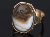 a gold ring with a carved image of a woman and a dragon