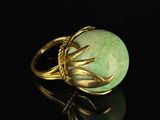 a close up of a gold ring with a green stone