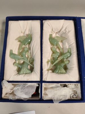 pair of green jade figurines in a blue box on a table