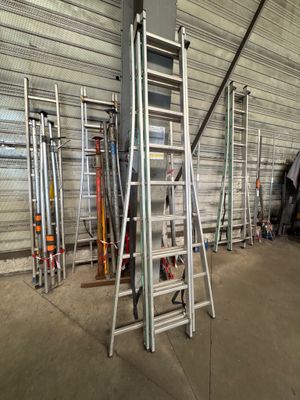 several ladders are lined up in a warehouse with a lot of tools