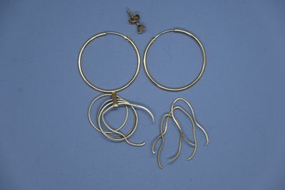 un gros plan sur une paire de boucles d'oreilles créoles en or posées sur une surface bleue