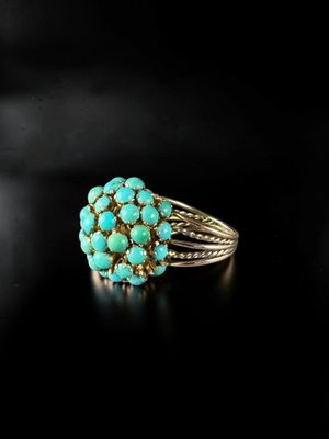 a close up of a turquoise stone ring on a black surface