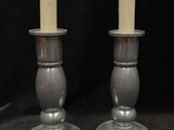 pair of silver candle holders with candles on a black background