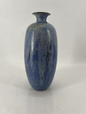un vase bleu posé sur une surface blanche