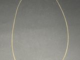un collier à chaîne en or avec un pendentif de forme carrée sur fond noir