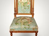 an old chair with a floral upholstered back and a wooden frame