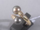 pair of pearl and diamond rings sitting on a black stand