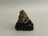 une petite figurine représentant une femme assise sur un rocher