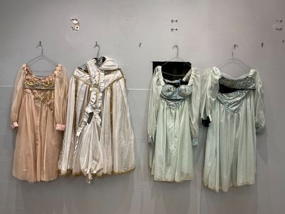 trois robes accrochées à un mur dans une vitrine de musée