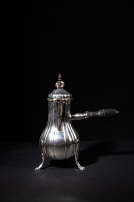 an antique silver coffee pot sitting on top of a black table