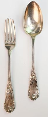 trois cuillères et une fourchette en argent sur une surface blanche
