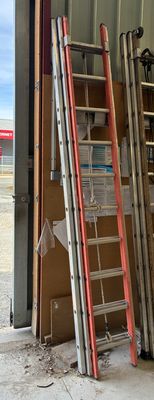 Plusieurs échelles sont appuyées contre un mur dans un garage.