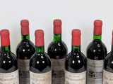 six bottles of red wine lined up in a row on a table