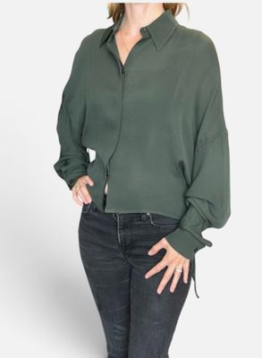 La femme, vêtue d'un t-shirt vert et d'un jean, prend la pose pour une photo.