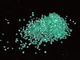 a close up of a pile of green crystals on a black surface