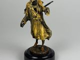 une statue représentant un homme armé, posée sur un socle noir