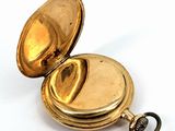 a gold pocket watch sitting on a white surface