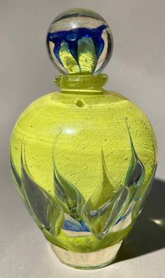 un vase en verre jaune orné d'une fleur bleue