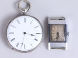 a silver pocket watch and a silver watch on a white surface