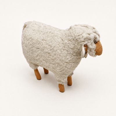 a stuffed sheep that is standing on a white surface