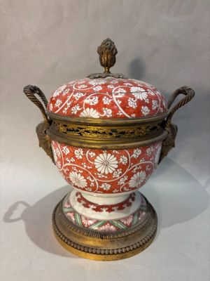 a red and white vase with a gold lid