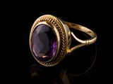 a close up of a gold ring with a purple stone