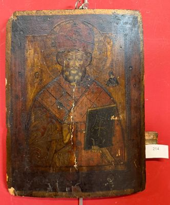 an old wooden icon of a man holding a book on a red wall