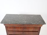 an image of a marble top chest of drawers against a white wall