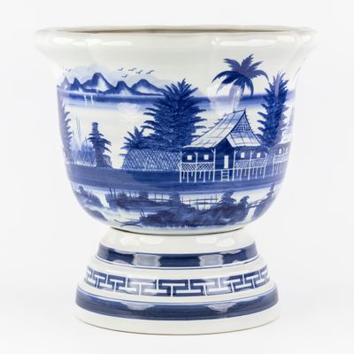un vase bleu et blanc sur lequel est représentée une maison