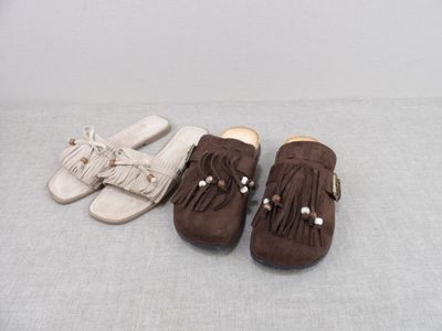 Deux paires de chaussures et une paire de pantoufles sont posées sur un lit.