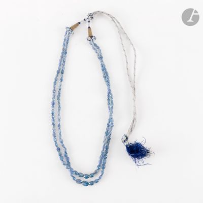 collier composé de perles de verre bleues et d'une breloque en forme de plume bleue sur fond blanc