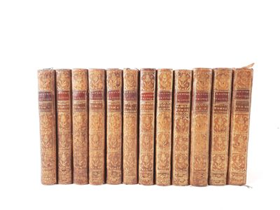six old books are lined up in a row on a white surface