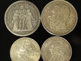 four different types of silver coins on a black surface