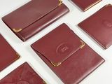 six portefeuilles en cuir rouge rehaussés de détails dorés sur fond blanc