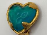 a close up of a heart shaped broochle on a white surface