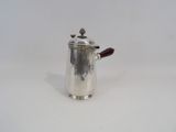 a silver coffee pot with a wooden handle on a white surface