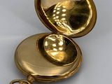 an image of a gold pocket watch on a white surface