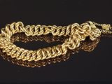 gros plan d'un bracelet en chaîne en or sur une surface noire