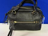 a black leather handbag with gold hardware and zippers