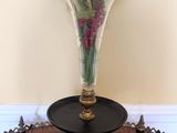 un vase en verre avec des fleurs posé sur une table dans une pièce