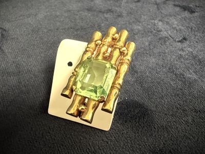 a close up of a ring with a green stone in it